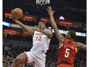 Virginia guard De'Andre Hunter (12) attempts a shot over the reach of Louisville center Malik Williams (5) during the first half of an NCAA college basketball game in Louisville, Ky., Saturday, Feb. 23, 2019.