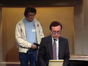 This Aug. 20, 1987, image made from video shows an intruder with a gun, as journalist David Horowitz is taken hostage during a live broadcast of Channel 4 Los Angeles. Horowitz remained calm and read the gunman's statements on camera, but the station had cut the broadcast without the gunman becoming aware of that fact. The gun turned out to be a toy BB gun, and Horowitz then took on the campaign to ban toy guns that look like real guns. Longtime consumer journalist David Horowitz has died at age 81, his wife told NBC4. (NBC-TV via AP)