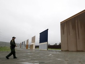 In this Feb. 5, 2019 file photo a Border Patrol agent walks towards prototypes for a border wall in San Diego.