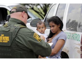 FILE - In this June 25, 2018, file photo, a mother migrating from Honduras holds her 1-year-old child as surrendering to U.S. Border Patrol agents after illegally crossing the border near McAllen, Texas. The Trump administration says it would require extraordinary effort to reunite what may be thousands of migrant children who have been separated from their parents and, even if it could, the children would likely be emotionally harmed.