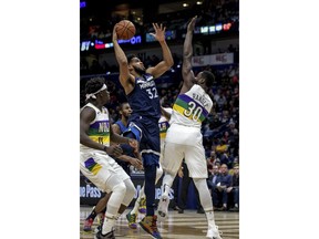 Minnesota Timberwolves center Karl-Anthony Towns (32) shoots between New Orleans Pelicans guard Jrue Holiday (11) and center Julius Randle (30) during the first half of an NBA basketball game in New Orleans, Friday, Feb. 8, 2019.