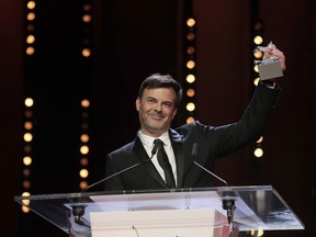 Director Francois Ozon holds aloft the Silver Bear grand jury prize for the film 'By the Grace of God' onstage at the award ceremony of the 2019 Berlinale Film Festival in Berlin, Germany, Saturday, Feb. 16, 2019.