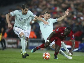 Liverpool's Sadio Mane, right, competes for the ball with Bayern midfielder Javi Martinez, left, and Bayern midfielder Joshua Kimmich, back center, during the Champions League round of 16 first leg soccer match between Liverpool and Bayern Munich at Anfield stadium in Liverpool, England, Tuesday, Feb. 19, 2019.