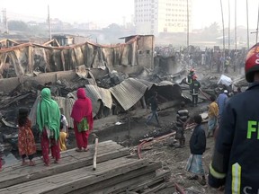 People gather to watch as firefighters damp down the area following a deadly fire in a poor residential area of the seaport city Chattogram, southern Bangladesh, Sunday Feb. 17, 2019. At least eight people are feared dead after a fire engulfed the residential area, razing some 200 closely packed houses to the ground, fire service said Sunday. (AP Photo)