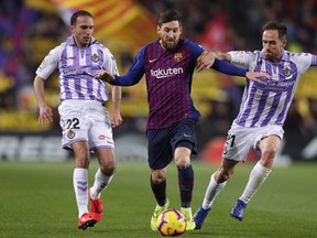 Barcelona forward Lionel Messi, center, challenges for the ball with Valladolid's Nacho Martinez, left, and Michel Herrero during the Spanish La Liga soccer match between FC Barcelona and Valladolid at the Camp Nou stadium in Barcelona, Spain, Saturday, Feb. 16, 2019.