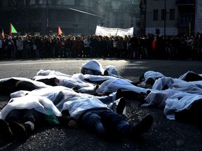 Activists lie on the ground as they take part in a protest against Italian Interior Minister Matteo Salvini's migrant and security decree, in Milan, Italy, Saturday, Feb. 16, 2019.