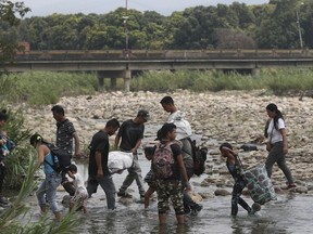 Venezuelans use the Tachira river as a crossing point on the Colombia and Venezuela border, with the Simon Bolivar International Bridge in the background, in La Parada, Colombia, Thursday, Feb. 28, 2019. The border between Colombia and Venezuela has been closed indefinitely by the Venezuelan government.