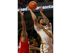 Minnesota's Jordan Murphy (3) shoots as he is fouled by Indiana's Juwan Morgan, right, as De'Ron Davis, left, helps to defend in the first half of an NCAA college basketball game Saturday, Feb. 16, 2019, in Minneapolis.