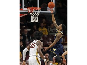 Michigan's Charles Matthews, right, lays up a shot as Minnesota's Daniel Oturu watches in the first half of an NCAA college basketball game Thursday, Feb. 21, 2019, in Minneapolis.