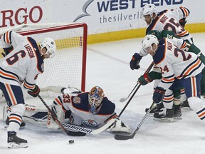 Edmonton Oilers' Adam Larsson, left, of Sweden, and Brad Malone, right, assist goalie Cam Talbot as Minnesota Wild's Zach Parise, in middle at right, can't reach the rebound during the first period of an NHL hockey game Thursday, Feb. 7, 2019 in St. Paul, Minn.