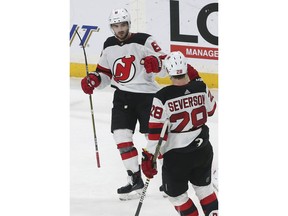 New Jersey Devils' Damon Severson, right, congratulates Will Butcher after Butcher's goal against Minnesota Wild goalie Devan Dubnyk in the second period of an NHL hockey game Friday, Feb.15, 2019, in St. Paul, Minn.