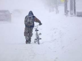 Austin Tauber heads home with his bicycle Wednesday morning, Feb. 20, 2019, in the snow in Anoka, Minn. Forecasters are warning residents in parts of Minnesota and western Wisconsin the advancing winter storm could produce up to 9 inches of snow.