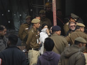 Policemen and others stand at the spot after an early morning fire at the Arpit Palace Hotel killed more than a dozen people in the Karol Bagh neighborhood of New Delhi, India, Tuesday, Feb.12, 2019.