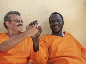 In this photo taken Friday, Nov. 2, 2018, James Gatdet Dak, right, the longtime spokesman of opposition leader Riek Machar, clasps hands with William Endley, left, a South African former defense colonel who also worked with the opposition, as they prepare to be released from prison after their death sentence was pardoned, in Juba, South Sudan. Dak, one of the highest-profile detainees during South Sudan's five-year civil war, has shared his account with The Associated Press, after his release under a fragile peace deal signed in September.