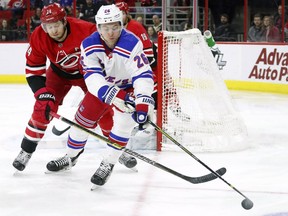 Carolina Hurricanes' Jaccob Slavin, left, and New York Rangers' Jimmy Vesey, right,  vie for the puck during the first period of an NHL hockey game in Raleigh, N.C., Tuesday, Feb. 19, 2019.