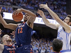 Virginia's De'Andre Hunter (12) and North Carolina's Luke Maye reach for a rebound during the first half of an NCAA college basketball game in Chapel Hill, N.C., Monday, Feb. 11, 2019.