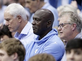 Charlotte Hornets owner and former North Carolina great Michael Jordan, center, watches North Carolina play Virginia during an NCAA college basketball game in Chapel Hill, N.C., Monday, Feb. 11, 2019. At right is former North Carolina player Buzz Peterson, assistant general manager of the Hornets, and at left is former North Carolina player Mitch Kupchak, general manager of the Hornets. Peterson knew Jordan as well as anyone when they were in college. Roommates and teammates at North Carolina, they spent countless days competing on the basketball court in practice and endless hours talking hoops. But Peterson never saw this coming: His roommate becoming an NBA owner and hosting the league's All-Star game in his home state of North Carolina.