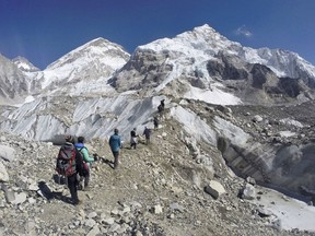 FILE - In this Monday, Feb. 22, 2016 file photo, trekkers pass through a glacier at the Mount Everest base camp, Nepal. One-third of Himalayan glaciers will melt by the end of the century due to climate change, threatening water sources for 1.9 billion people, even if current efforts to reduce climate change succeed, according to an assessment released Monday, Feb. 4, 2019. by the International Centre for Integrated Mountain Development.