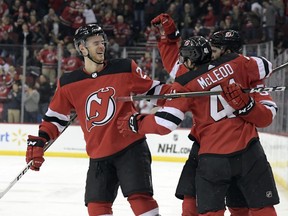 New Jersey Devils center Kevin Rooney celebrates his short-handed goal with Michael McLeod (41) and Mirco Mueller, left, during the second period of an NHL hockey game against the Calgary Flames Wednesday, Feb. 27, 2019, in Newark, N.J.