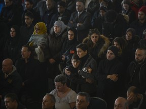 A woman and child embrace while standing with hundreds of others as officials read the names of the seven Barho siblings during the funeral for the Syrian refugees in Halifax on Saturday.