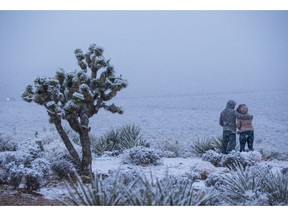 James Minner, of Las Vegas, left, and Candace Reid, of Albuquerque, N.M., watch as snow falls around the overlook at the Red Rock Canyon National Conservation Area outside of Las Vegas on Wednesday, Feb. 20, 2019.