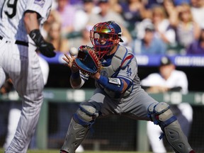 FILE - In this June 2, 2018, file photo, Los Angeles Dodgers catcher Yasmani Grandal fields the throw from left fielder Matt Kemp to put out Colorado Rockies' Charlie Blackmon during the first inning of a baseball game in Denver. The Milwaukee Brewers upgraded their catching situation when they finalized an $18.25 million, one-year contract with Grandal in January. Manny Pina, veteran journeyman Erik Kratz and prospect Jacob Nottingham also are in the mix behind the plate.