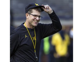 FILE - In this Nov. 25, 2017, file photo, Michigan head coach Jim Harbaugh adjusts his cap on the field during warmups before an NCAA college football game against Ohio State in Ann Arbor, Mich. Michigan finished the football recruiting cycle with the top-ranked class in the Big Ten for the first time since 2007, and four other conference programs were ranked in the top 25.