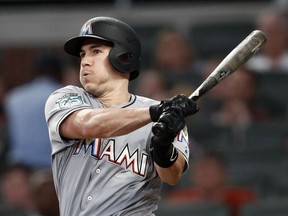 FILE - In this Tuesday, Aug. 14, 2018 file photo, Miami Marlins' J.T. Realmuto follows through on two-run base hit in the fourth inning of a baseball game against the Atlanta Braves in Atlanta. A person familiar with the negotiations says Miami Marlins All-Star catcher J.T. Realmuto has been traded to the Philadelphia Phillies for catcher Jorge Alfaro, two pitching prospects and international bonus pool allocation. The person confirmed the trade to The Associated Press on condition of anonymity Thursday, Feb. 7, 2019 because the teams had not announced it.