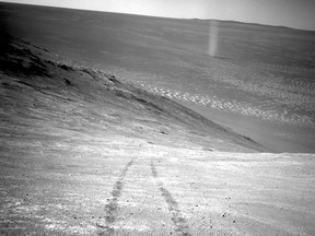 This March 31, 2016 photo made available by NASA shows a dust devil in a valley on Mars, seen by the Opportunity rover perched on a ridge. The view looks back at the rover's tracks leading up the north-facing slope of "Knudsen Ridge," which forms part of the southern edge of "Marathon Valley." (NASA/JPL-Caltech via AP)