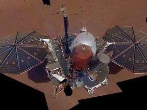 This Dec. 6, 2018 image made available by NASA shows the InSight lander. The scene was assembled from 11 photos taken using its robotic arm. The two white stalks between the center and the solar panels are weather sensors. Starting Tuesday, Feb. 19, 2019, NASA's Jet Propulsion Laboratory is posting the high and low temperatures online, along with wind speed and atmospheric pressure from the InSight lander. (NASA via AP)