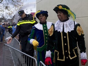 FILE - In this Nov. 18, 2017, file photo, Black Petes and police officers leave after the arrival of Sinterklaas, or Saint Nicholas in Dokkum, northern Netherlands. Confrontations broke in the Netherlands over supporters and opponents of the divisive helper of the Dutch version of Santa Claus. The helper, known as Black Pete, is played by whites in blackface at children's events.