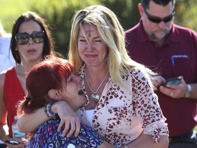 FILE - In this Feb. 14, 2018, file photo, Mechelle Boyle, right, embraces Cathi Rush as they wait for news after reports of a shooting at Marjory Stoneman Douglas High School in Parkland, Fla. The image become emblematic of the Parkland school massacre: two terrified moms outside the school, one of them a tall, weeping blonde with the black smudge of Ash Wednesday on her forehead, the other a petite redhead crying in despair on her shoulder.