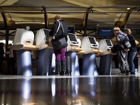 FILE - In this Jan. 30, 2017 file photo, passengers check in for Delta Air Lines flights at kiosks at Hartsfield-Jackson Atlanta International Airport in Atlanta. Major U.S. airlines say they will soon change their ticketing process to give passengers an option to identifying themselves as male or female. The gender option on airline sites will soon include choices such as "Mx." or "undisclosed." American, Delta and United confirmed Friday, Feb. 15, 2019, that they are in the process of updating their booking tools to add such an option. They said the change will be made in the next several weeks.