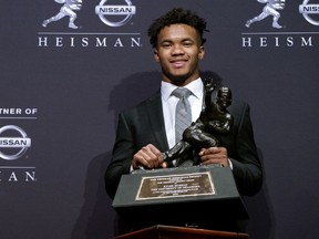 FILE - In this Dec. 8, 2018, file photo, Oklahoma quarterback Kyler Murray holds the Heisman Trophy after winning the award in New York. Before picking football over baseball, Kyler Murray got some advice from another famous two-sport star. Tim Tebow says he told Murray to follow his heart when deciding between the Oakland Athletics and pursuing an NFL career.