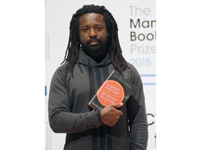 FILE - In this Oct. 12, 2015 file photo, author Marlon James poses with his book "A Brief History of Seven Killings" in London. Author of four novels, the 48-year-old James has made an art of "finding what would rather stay lost," as he writes in his new work, "Black Leopard, Red Wolf."