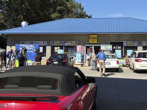 FILE - In this Oct. 24, 2018, file photo, media, left record people entering the KC Mart in Simpsonville, S.C., after it was announced the winning Mega Millions lottery ticket was purchased at the store. Unless the winner chooses to come forward, the world may never know who won. The winner of a $1.537 billion lottery jackpot in South Carolina has yet to come forward. That means the state of South Carolina might be a big loser too. With the prize unclaimed, the state Board of Economic Advisors is expected Thursday, Feb. 14, 2019, to suggest removing the $61 million windfall from the state spending plan.