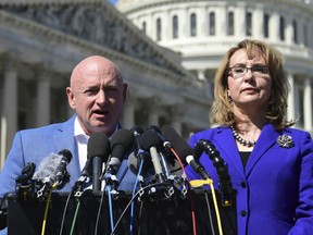 FILE- In this Oct. 2, 2017, file photo former Rep. Gabrielle Giffords, D-Ariz., right, listens as her husband Mark Kelly, left, speaks on Capitol Hill in Washington. Kelly said Tuesday, Feb. 12, 2019, that he's running to finish John McCain's term in the U.S. Senate.