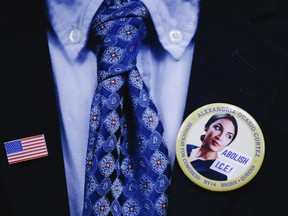 A supporter wears an American flag pin and an Ocasio-Cortez campaign pin to attend the swearing-in ceremony and inaugural address of Rep. Alexandria Ocasio-Cortez, D-N.Y. at the Renaissance School for Musical Theater and Technology in the Bronx borough of New York on Saturday, Feb. 16, 2019.