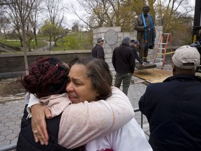 FILE - In this Tuesday, April 17, 2018, file photo, Dr. Bernadith Russell hugs a friend as the statue of Dr. J. Marion Sims, is removed from New York's Central Park. Sims was known as the father of modern gynecology, but critics say his use of enslaved African-American women as experimental subjects was unethical. Russell, a gynecologist, said at the time she was in medical school, "He was held up as the father of gynecology with no acknowledgement of the enslaved women he experimented on."