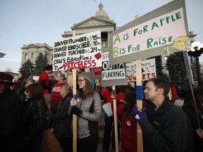 FILE - In this Wednesday, Jan. 30, 2019, file photo, teachers from the Denver Public Schools carry placards as they wait to march after a rally in support of a strike outside the State Capitol in Denver. Denver teachers are planning to strike Monday, Feb. 11, 2019 after failed negotiations with the school district over base pay.