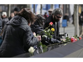 Friends and family of the victims of the 1993 World Trade Center bombing, including Stephen Knapp, right, place flowers over the names of the victims during a ceremony to commemorate the bombing at the 9/11 Memorial in New York, Tuesday, Feb. 26, 2019.