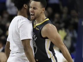 Golden State Warriors' Stephen Curry, right, celebrates a score with Quinn Cook during the second half of the team's NBA basketball game against the Utah Jazz on Tuesday, Feb. 12, 2019, in Oakland, Calif.