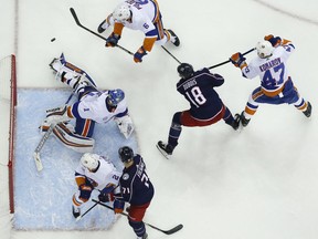 New York Islanders' Thomas Greiss, left, of Germany, makes a save against the Columbus Blue Jackets as players look for the rebound during the second period of an NHL hockey game Thursday, Feb. 14, 2019, in Columbus, Ohio.