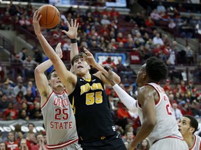 Iowa forward Luka Garza, center, goes up for a shot between Ohio State forward Kyle Young, left, and forward Andre Wesson during the first half of an NCAA college basketball game in Columbus, Ohio, Tuesday, Feb. 26, 2019.