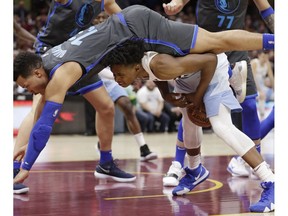 Dallas Mavericks' Jalen Brunson, top, jumps over Cleveland Cavaliers' Collin Sexton in the first half of an NBA basketball game, Saturday, Feb. 2, 2019, in Cleveland. Brunson was called for the foul.