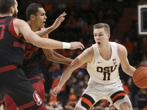 Oregon State's Zach Reichle (11) looks for a way past Stanford's Josh Sharma (20) and Oscar da Silva (13) during the first half of an NCAA college basketball game in Corvallis, Ore., Thursday, Feb. 7, 2019.