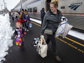 Jordyn Hooper, right, and her four-year-old daughter Quinn Hooper, left, join other passengers as they disembark from an Amtrak train in Eugene, Ore, Tuesday, Feb. 26, 2019 after being stranded overnight in the mountains east of town.