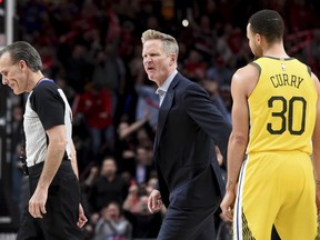 Golden State Warriors coach Steve Kerr, center, yells at referee Ken Mauer, left, after being called for a technical foul, while guard Stephen Curry, right, watches during the second half of an NBA basketball game against the Portland Trail Blazers in Portland, Ore., Wednesday, Feb. 13, 2019. The Blazers won 129-107.