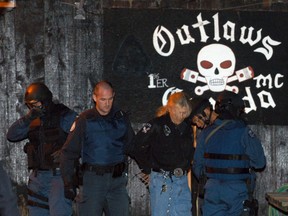 Police officers lead away two people arrested in a 2002 multi-force raid on an Outlaws clubhouse. Officers seized weapons and ammunition.