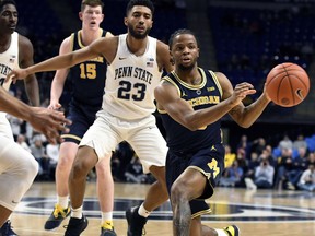 Michigan guard Zavier Simpson (3) passes the ball as Penn State guard Josh Reaves (23) defends during the first half of an NCAA college basketball game, Tuesday, Feb. 12, 2019, in State College, Pa.